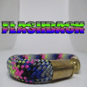 Può includere: Un braccialetto in paracord multicolore con una chiusura in ottone a forma di bossolo di proiettile. Il braccialetto presenta paracord rosa, verde, blu, nero e grigio.