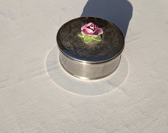 Caja de baratijas vintage de metal en tono plateado, tapa estilo Art Nouveau con rosa de cerámica, alrededor de los años 50.