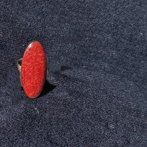 Puede incluir: Un anillo de plata con una piedra de coral roja de forma ovalada.