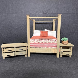 May include: Miniature bedroom set with a four-poster bed, dresser, and nightstand. The bed has a red and white patterned comforter and pillow. The furniture is made of light-colored wood.