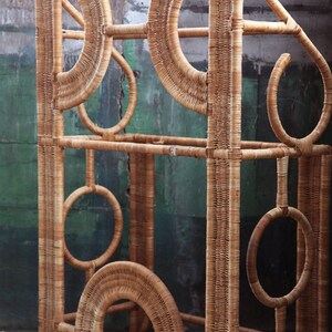 May include: A tall, woven wicker shelf unit with a geometric design. The shelf has multiple levels and is made of natural brown wicker.