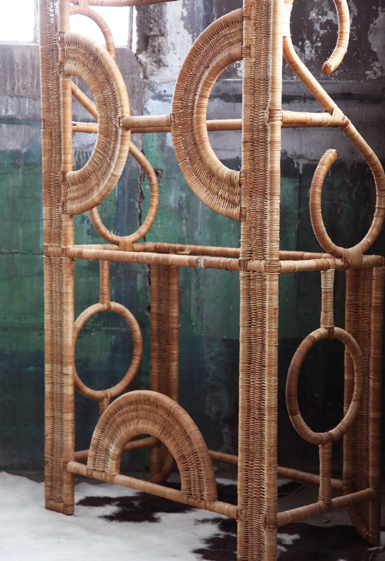 May include: A tall, woven wicker shelf unit with a geometric design. The shelf has multiple levels and is made of natural brown wicker.
