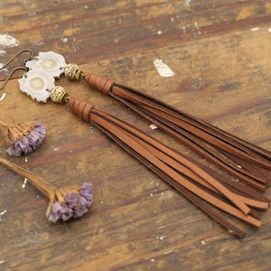 以下が含まれることがあります： 白と茶色の瑪瑙のペンダントが付いた、長い茶色の革のタッセルイヤリングのペア