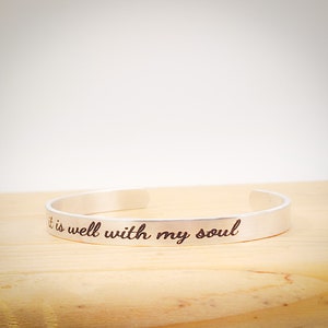 May include: Silver bangle bracelet with the inscription "It is well with my soul".
