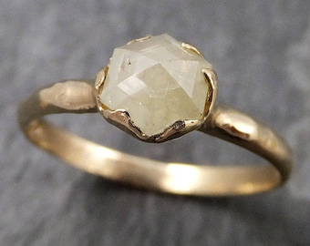 May include: A gold ring with a large, faceted, white gemstone set in a textured band.