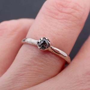 Puede incluir: Un anillo de plata con una piedra preciosa gris oscuro de corte &aacute;spero.