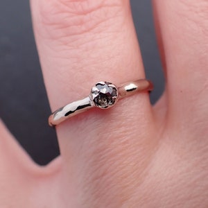 Puede incluir: Un anillo de plata con una banda martillada y una piedra preciosa redonda de color gris oscuro.