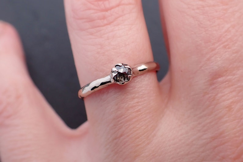 Puede incluir: Un anillo de plata con una banda martillada y una piedra preciosa redonda de color gris oscuro.