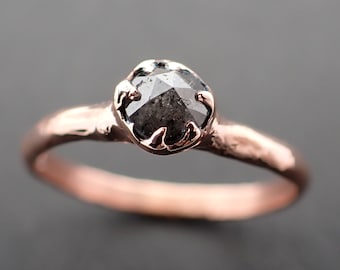 May include: A rose gold ring with a black diamond set in a delicate, claw-like setting.