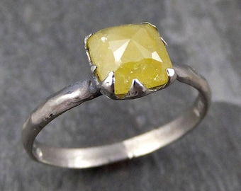 May include: A silver ring with a yellow, square-shaped gemstone set in a claw setting.