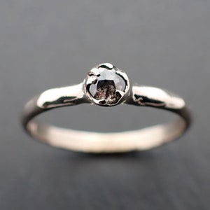 Puede incluir: Un anillo de plata con un diamante negro engastado en una banda texturizada.