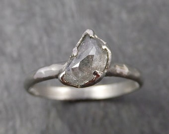 May include: A silver ring with a large, clear, faceted, grey diamond set in a crescent shape.