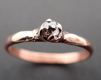 May include: A rose gold ring with a black diamond set in a rough, textured band.