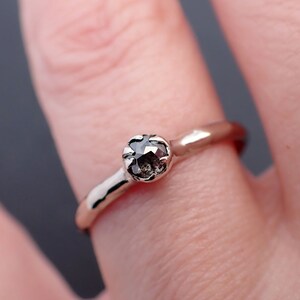 Puede incluir: Un anillo de banda de oro simple con un solo diamante redondo gris oscuro.