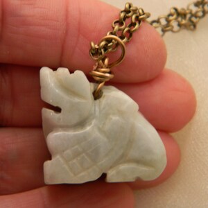 May include: A white jade pendant carved in the shape of a dragon, hanging from a gold chain.