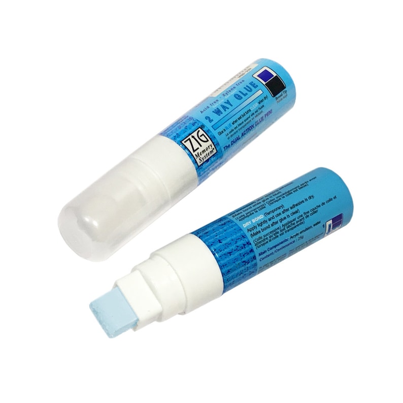 May include: Two blue and white Zig Memory System 2-Way Glue pens. The pens have a blue and white patterned design and say "Acid free - Xylane tree" and "The Dual Action Glue Pen".