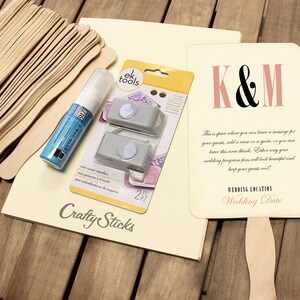 May include: A set of wedding DIY supplies including a pack of wooden craft sticks, a bottle of blue paint, two corner rounders, and a sign with the text "K&M" and "Wedding Location Wedding Date".