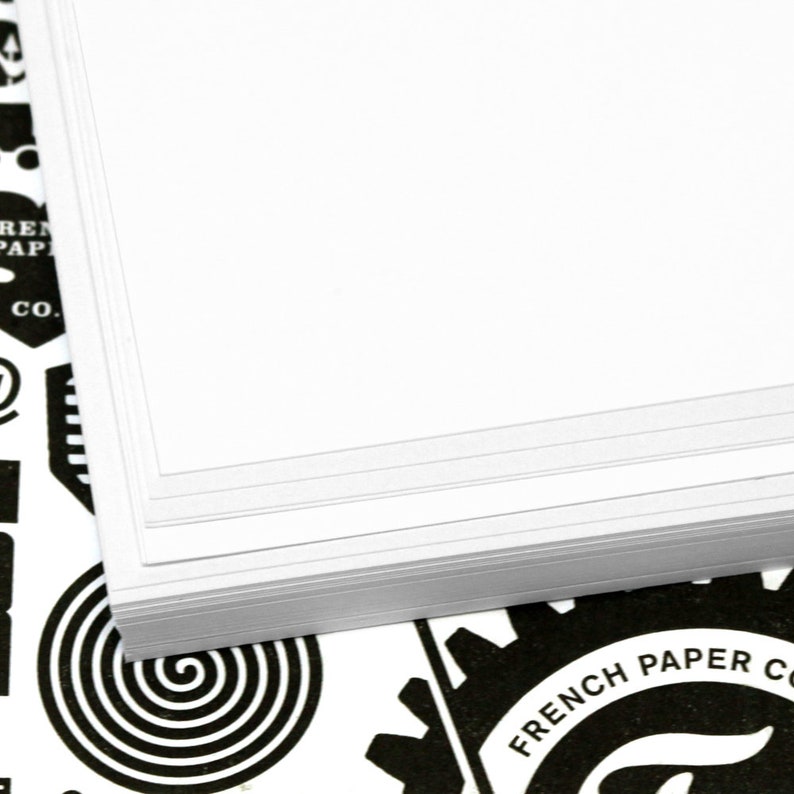K&ouml;nnte beinhalten: Ein Stapel wei&szlig;es Papier mit einem schwarz-wei&szlig;en Logo, auf dem unten "French Paper Co." steht.