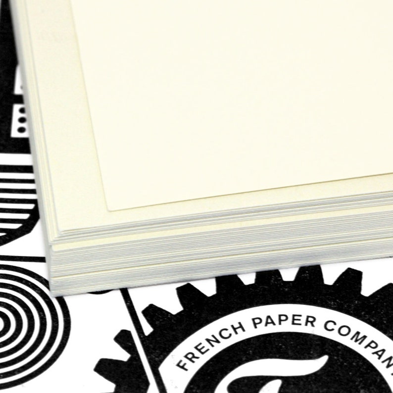 May include: A stack of white paper sheets with a black and white gear logo that says "French Paper Company" on it.