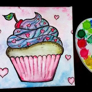 May include: A watercolor painting of a pink cupcake with blue and purple frosting and a red cherry on top. The cupcake is surrounded by pink hearts.