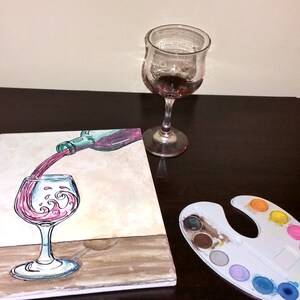 May include: A painting of a wine bottle pouring red wine into a glass. The glass has a wave design in the wine. The painting is on a canvas and there is a paint palette with various colors of paint in the background.