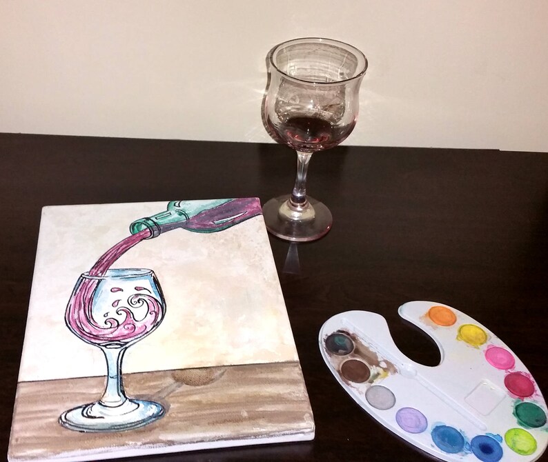 May include: A painting of a wine bottle pouring red wine into a glass. The glass has a wave design in the wine. The painting is on a canvas and there is a paint palette with various colors of paint in the background.