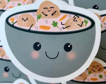 May include: A gray bowl with a smiling face and blush on its cheeks. The bowl is filled with a pink broth and three cartoon meatballs with smiling faces. The meatballs are floating in the broth with their arms and legs sticking out. The bowl is decorated with stars and carrots.