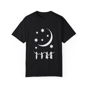 May include: Black t-shirt featuring a white crescent moon and stars design. Four figures are holding hands below the moon and stars.