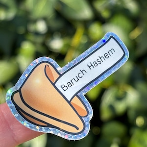May include: A holographic sticker of a fortune cookie with the text "Baruch Hashem" on the fortune paper.