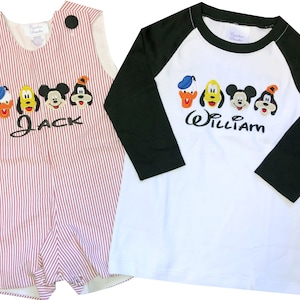 Puede incluir: Dos conjuntos infantiles. Uno es un pelele a rayas rojas y blancas con personajes de Mickey Mouse y el nombre "Jack". El otro es una camiseta blanca y negra de estilo béisbol con personajes de Mickey Mouse y el nombre "William".