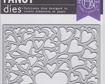 May include: A silver metal die set featuring a heart design. The die set has a large heart in the center, surrounded by various heart shapes and decorative elements. The packaging includes the text "FANCY dies" and "HERO ARTS".