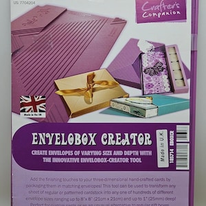 Può includere: Uno strumento viola Crafter's Companion Envelopox Creator con manico e stilo per cordonatura. La confezione mostra immagini di buste e scatole fatte a mano, con testo che include dimensioni fino a 21 cm x 21 cm e 25 mm di profondità.