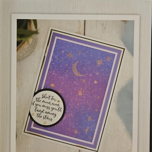 Könnte beinhalten: Himmelblaue 3D-Prägeordner mit einem lila-blauen Design mit einem Halbmond und Sternen. Die Ordnergröße beträgt 15,2 cm x 10,2 cm. Enthält das Zitat: "Ziele nach dem Mond, auch wenn du ihn verfehlst, landest du zwischen den Sternen."