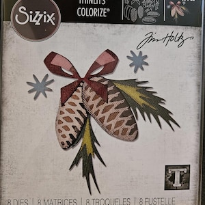 Puede incluir: Juego de troqueles Sizzix Thinlits Colorize con un diseño detallado de dos piñas con un lazo y detalles de estrellas. Las formas troqueladas son en tonos marrón, verde y rosa. El paquete incluye 8 troqueles.