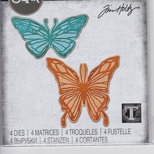 Könnte beinhalten: Eine Packung mit vier ausgestanzten Schmetterlingsformen zum Basteln. Die Schmetterlinge sind in zwei Farben: Türkis und Orange. Die Packung enthält den Text "THINLITS®" und "Sizzix" sowie die Nummer "666564".