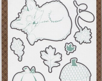 May include: A set of eight etched metal dies for crafting. The dies include a sleeping fox, an acorn, a pumpkin, and various leaves. The dies are outlined in blue and the text "Fall Breeze by Traci Smith" and "Etched Dies 8 shapes" is visible.