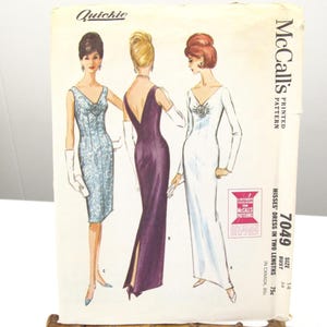 May include: Vintage McCall's sewing pattern for misses' dresses in two lengths. The pattern features illustrations of three dresses in various styles. The pattern is displayed on a bamboo easel. The text "Quickie" is visible at the top.