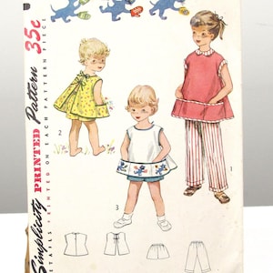 May include: A vintage Simplicity sewing pattern envelope 4384 for size 3, featuring illustrations of children wearing a yellow floral dress, a white top with blue shorts, and a red tunic with striped pants, with blue cat graphics at the top.