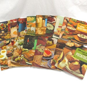 May include: A collection of vintage recipe books with colorful covers featuring various food images. The books are titled "250 ways to serve fresh vegetables" and "250 ways of serving potatoes".