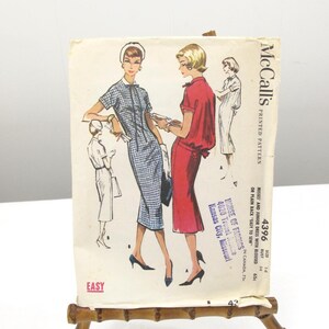 May include: Vintage McCall's printed sewing pattern, style 4396, featuring illustrations of dresses. The pattern is displayed on a bamboo easel. The text on the pattern reads "EASY" and "MISSES AND JUNIOR DRESS WITH BLOUD OR PLAIN BACK".