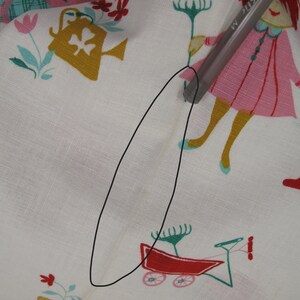 May include: White fabric with a colorful pattern of children playing. The fabric has a small tear in the center.