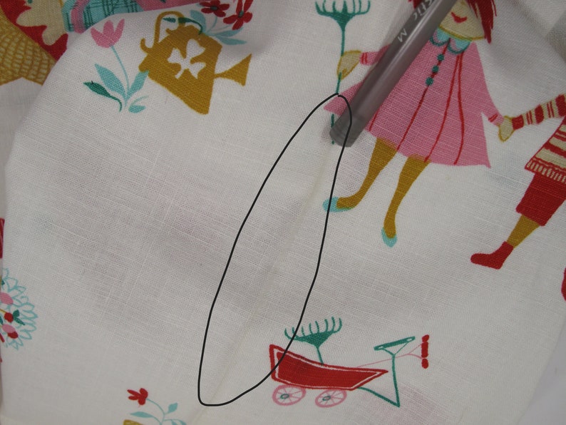 May include: White fabric with a colorful pattern of children playing. The fabric has a small tear in the center.