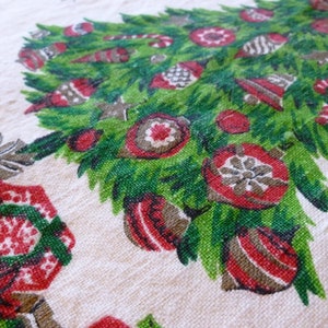 May include: A vintage Christmas tablecloth featuring a green Christmas tree with red and white ornaments. The tree is surrounded by a red and white floral design.