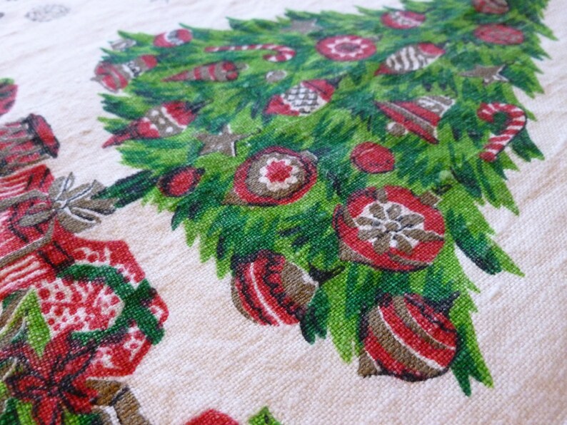 May include: A vintage Christmas tablecloth featuring a green Christmas tree with red and white ornaments. The tree is surrounded by a red and white floral design.