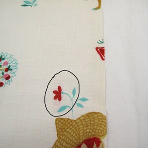 May include: White fabric with a red flower and green leaves printed on it. The flower is outlined in black.