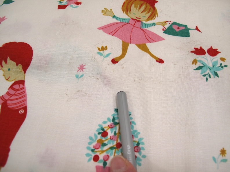 May include: White fabric with a repeating pattern of children and flowers. The children are dressed in red, pink, and green. The flowers are red, yellow, and blue.