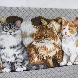 May include: Fabric featuring three detailed cat illustrations. The cats are in shades of gray, brown, and orange, with white accents. They are sitting on a gray patterned background, creating a cozy, feline-themed design.