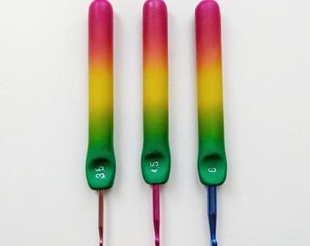 May include: Three crochet hooks with rainbow-colored handles. The handles transition from pink to yellow to green. The hook sizes are 3.5, 4.5, and 6, with corresponding brown, pink, and blue hooks. The hooks are arranged vertically.