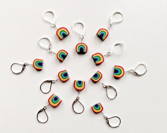 Può includere: Un set di 12 orecchini arcobaleno con ganci d'argento. Ogni orecchino presenta un design ad arco arcobaleno.
