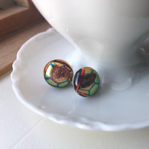 May include: A pair of iridescent glass earrings with a honeycomb pattern. The earrings are a mix of green, gold, and red.